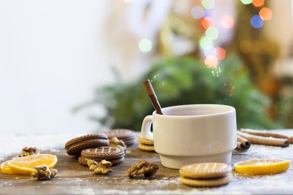 Tea, tangerines and cookies in Christmas decor with Christmas tree, nuts and apples on dark wooden background — Stock Photo, Image