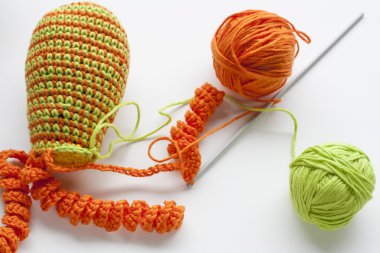 Making of handmade colorful crochet toys sweets (key ring) with skein on wooden table. Selective focus.