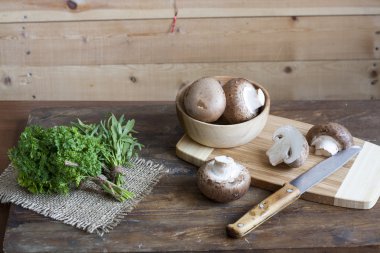 Champignon mantar, torbalama ve otlar ahşap arka plan üzerinde ahşap bir gemide