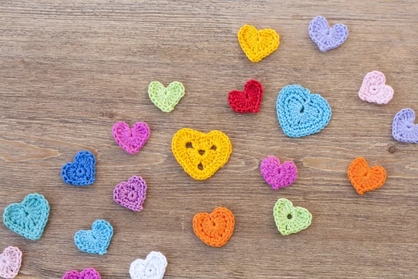 Many multicolor crochet hearts on wooden background for Valentines day — Stock Photo, Image