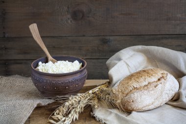 Rustik doğal süt ürünleri. Rustik doğal süt ürünleri süzme peynir ve ekmek, yumurta, soğan ve sarımsak buğday eski ahşap arka plan üzerinde.