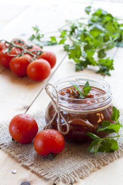 Cam maydanoz ve koyu ahşap masa, seçici odak üzerinde taze domates domates sosu (reçel).