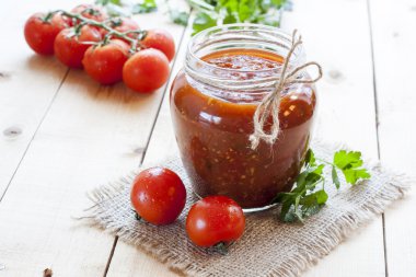 Cam maydanoz ve koyu ahşap masa, seçici odak üzerinde taze domates domates sosu (reçel).