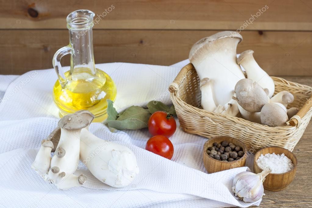 Basket with mushrooms, olive oil and ingredients for cooking on the wooden table of the kitchen background