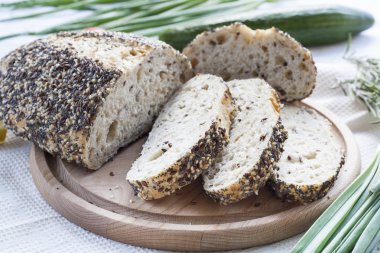 Ahşap masa, yuvarlak bir masa üzerine susam ve diğer tahıl ile ev yapımı ekmek ekmek dilimlenmiş