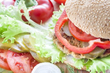 Ev yapımı hamburger, sebze ve otlar. Ev yapımı hamburger, domates, soğan, biber, marul ve dereotu ahşap tahta üzerinde dilimlenmiş.