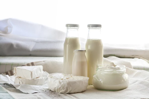 Dairy products. Milk in glass bottle, yogurt, sour milk cheese, sour cream, camembert and brie with checkered napkin on light blue wooden table — 스톡 사진