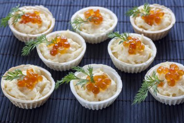 Tartlets with cream cheese and red caviar close up on the black background.