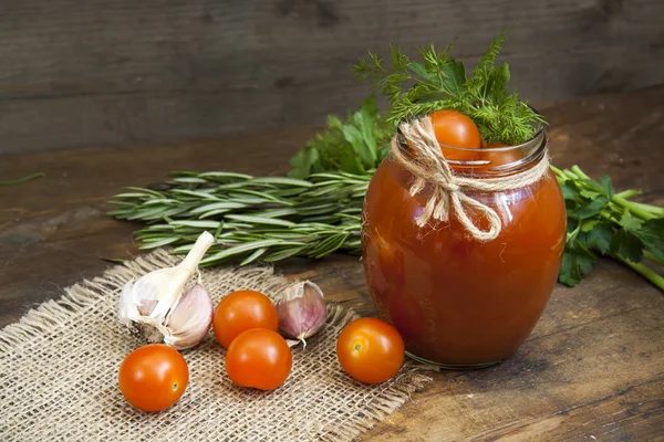 Canned marinated tomatoes in tomato juice on a wooden table — Stock Photo, Image