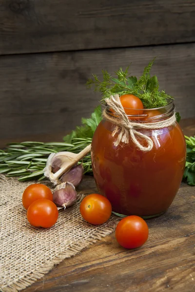 Canned marinated tomatoes in tomato juice on a wooden table — Stock Photo, Image