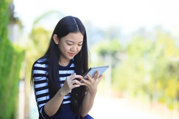 こぼれるような smil を手に立っているアジアの女の子とコンピューターのタブレット — ストック写真