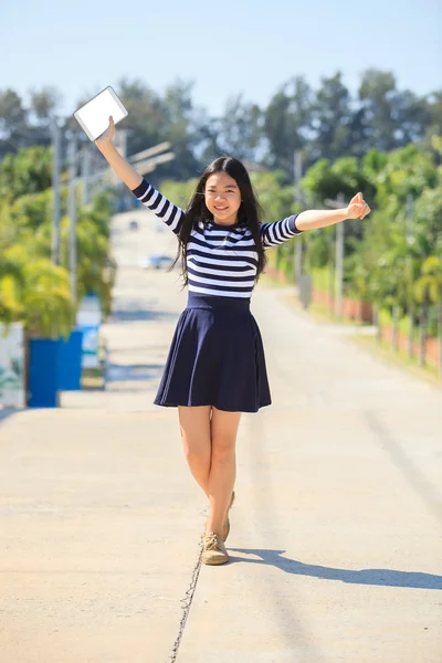 Asiatische Mädchen und Computer-Tablet in der Hand stehend mit zahmem Lächeln — Stockfoto