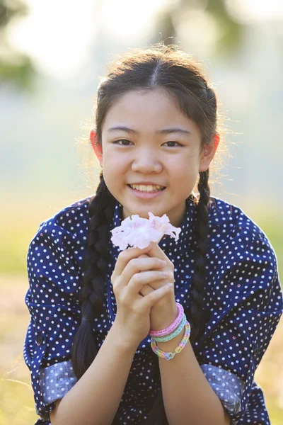 Tailandés 12s años niña sentada en jardín campo con flores de color rosa en — Foto de Stock