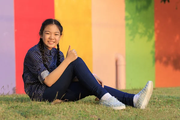 Asiatisches Mädchen entspannt auf grünem Rasen im öffentlichen Park sitzen — Stockfoto