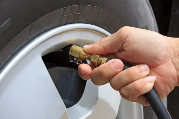 Mano y rueda del vehículo añadir presión de aire — Foto de Stock