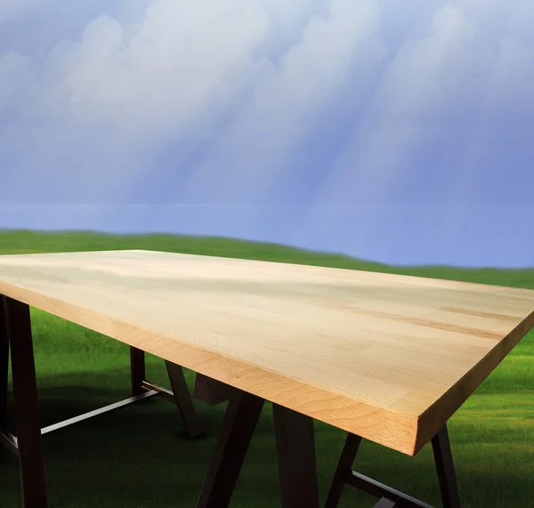 Зверху порожній дерев'яний стіл з природним зеленим трав'яним полем і синім — стокове фото