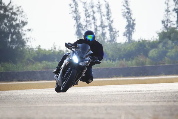 Young man riding big bike motorcycle against sharp curve of asphalt high ways road with rural lake scene use for male adventure activities and motor sport hobby on holiday vacation — Stock Photo, Image