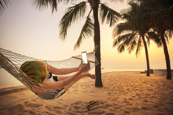 Mujer acostada en la cuna de la playa y tomando una fotografía por pho inteligente — Foto de Stock