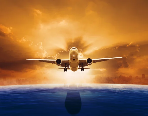 Passenger jet plane flying over beautiful sea level with sun set — Stock Photo, Image