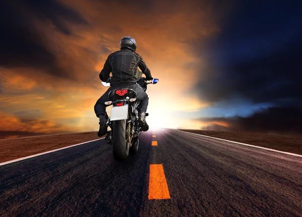 Hombre a caballo motocicleta en carretera contra hermoso sol puesta cielo —  Fotos de Stock