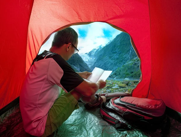 Camping man reading a traveling guild book in camp tent beautifu — Stock Photo, Image