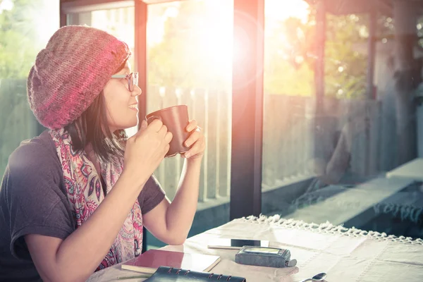 Asiatiska yngre kvinna och hett kaffe mugg i handen leende med happ — Stockfoto