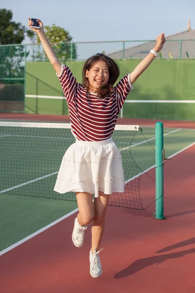Азиатка в спортивном теннисе прыгает со смайликом счастья — стоковое фото