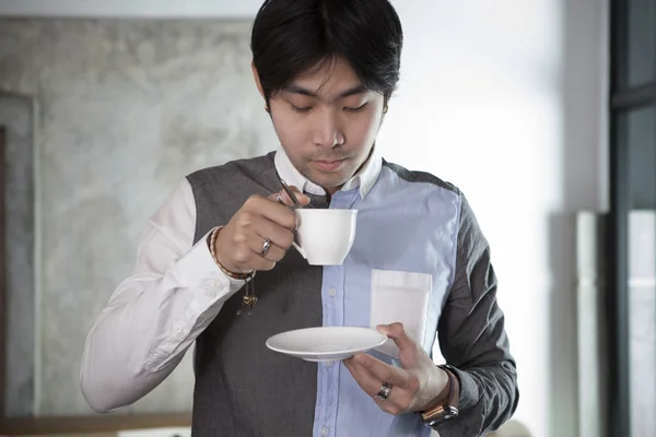 Asiatische jüngere Mann trinken Heißgetränk in weißen Becher — Stockfoto