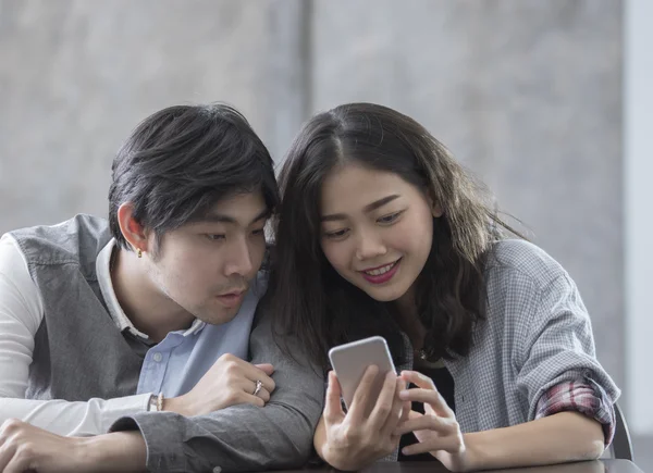 Aziatische jongere man en vrouw die kijken op smartphone met gelukkig f — Stockfoto
