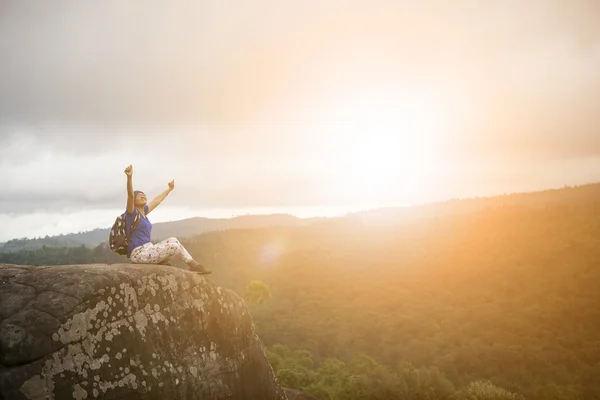 Backpacker Frau entspannt und Sieg Hand steigt auf Felsen Klippe — Stockfoto