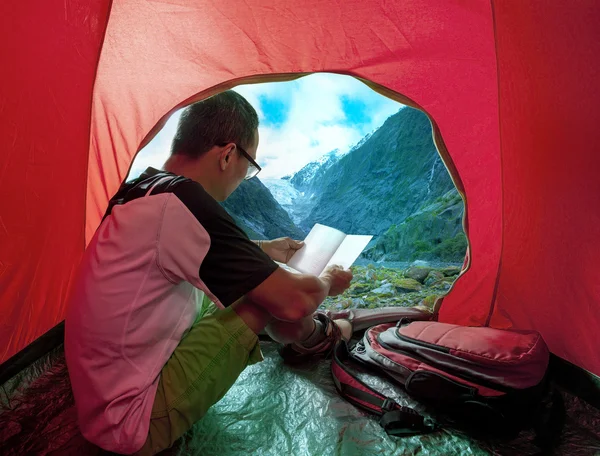 Camping man reading a traveling guild book in camp tent beautifu — Stock Photo, Image