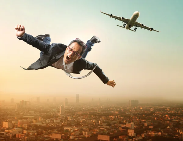 Homme d'affaires volant d'un avion de passagers survolant un gratte-ciel — Photo