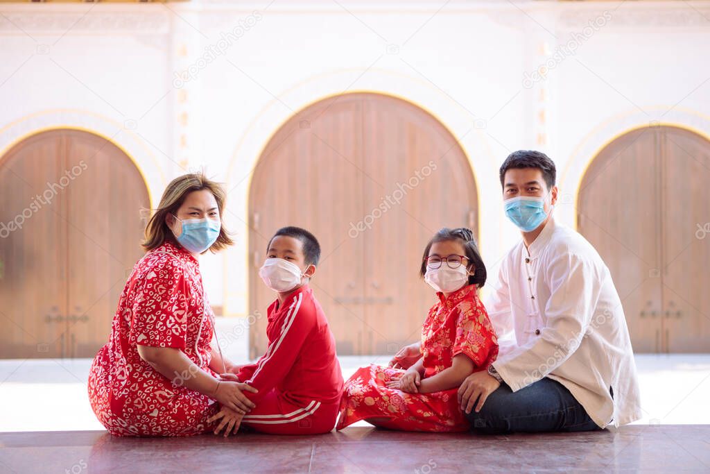 asian family wearing red chinese suit wearing protection mask sitting outdoor