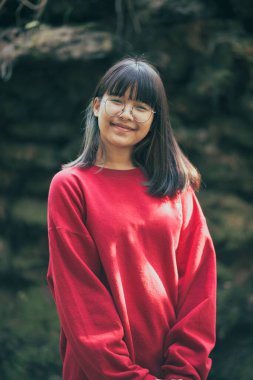 Dışarıda duran gözlüklü Asyalı bir gencin portresi.