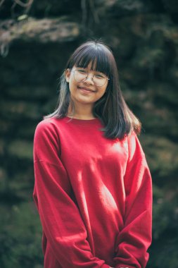 Dışarıda duran gözlüklü Asyalı bir gencin portresi.