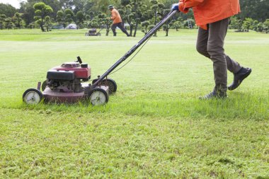 Worker cutting grass field with Lawn mower clipart