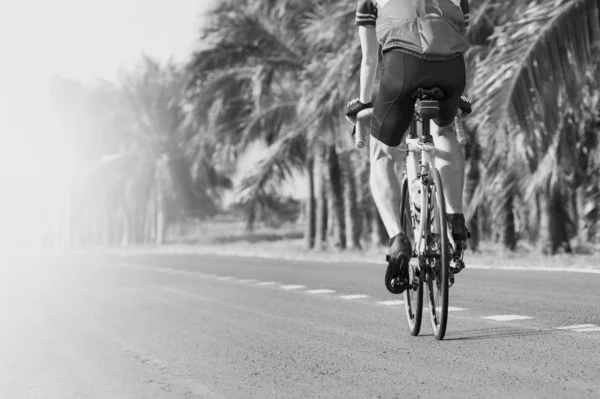 Young man riding road biking bycycle on asphalt track in black a — Stock Photo, Image