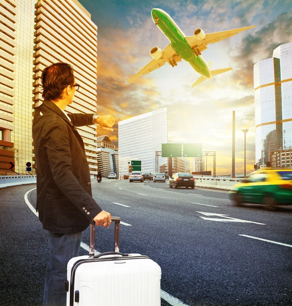 Traveler man and luggage standing on traffic and looking to time — Stock Photo, Image