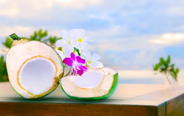 Slavenmarkt helft van groene kokosnoot water op hoogste houten tafel met tropica — Stockfoto