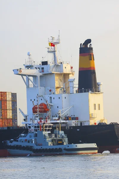 Remolcador junto a gran buque portacontenedores en línea fluvial —  Fotos de Stock