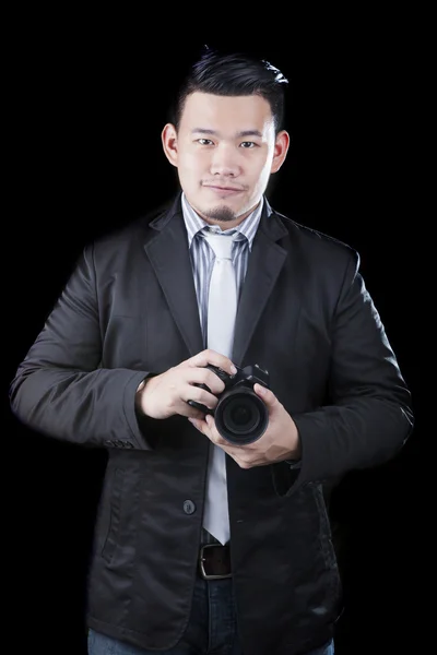 Молодий азіатський чоловік, що тримає камеру dslr, робить фотографію за низьким ключем — стокове фото