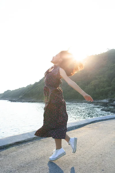 Hermosa mujer joven saltando en el lado del mar contra la iluminación del sol sobre el cielo — Foto de Stock