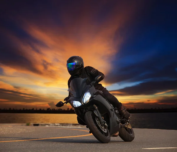 Young man riding big bike motorcycle leaning curve on asphalt hi — Stock Photo, Image