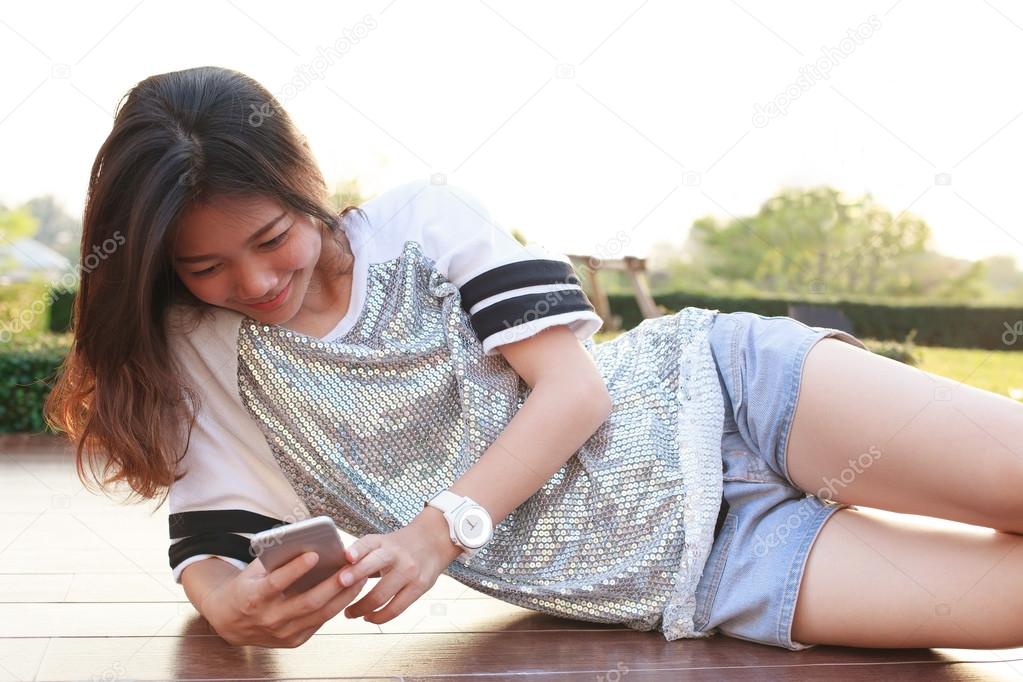 Portrait of young beautiful woman lying and reading text on smar