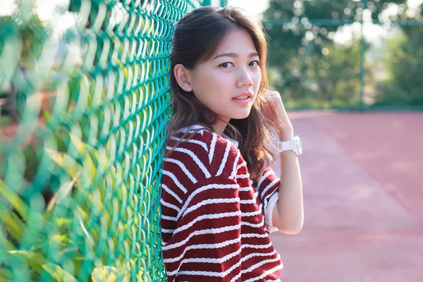 Portrait of beautiful young teen woman leaning steel net fence a — Stock Photo, Image