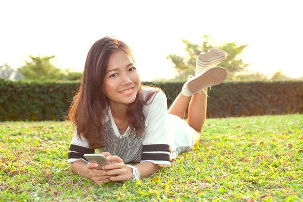 Portret van mooie jonge vrouw liggend op groen grasveld en — Stockfoto