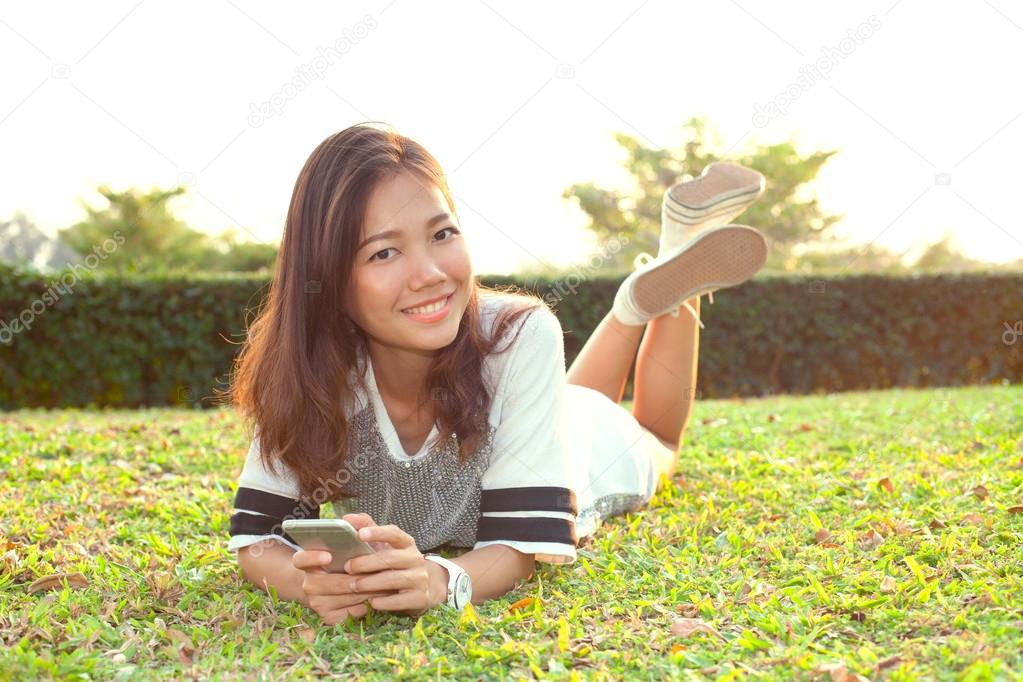portrait of beautiful young woman lying on green grass field and
