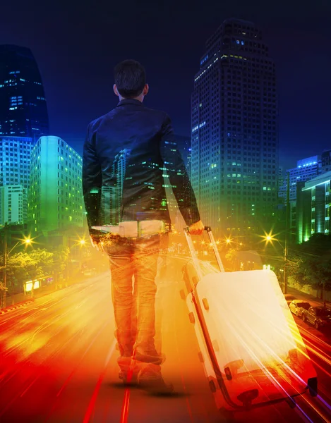Jonge man met reizen bagage tegen verlichting van stedelijke scen — Stockfoto