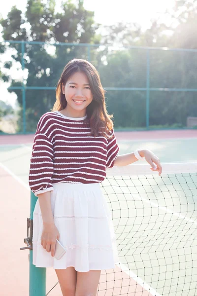 Porträt der schönen jungen Asiatin mit weißem Kleiderrock im Tenniskurs mit glücklichem Gesicht — Stockfoto