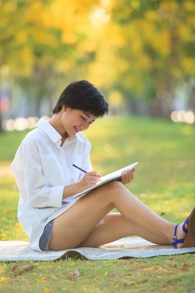 Joven hermosa asiático mujer escritura texto en diario libro en amarillo — Foto de Stock